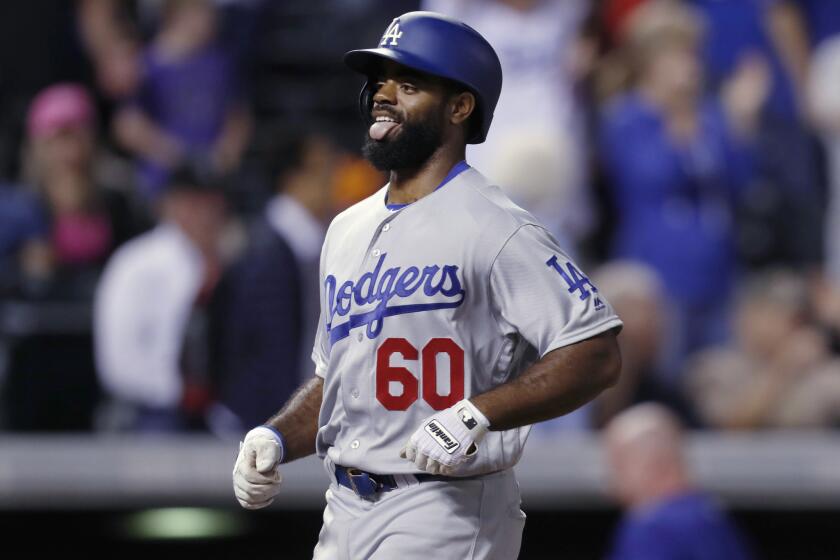 Dodgers outfielder Andrew Toles sticks out his tongue as he heads to home plate after hitting a go-ahead grand slam in the ninth inning off Rockies relief pitcher Adam Ottavino.