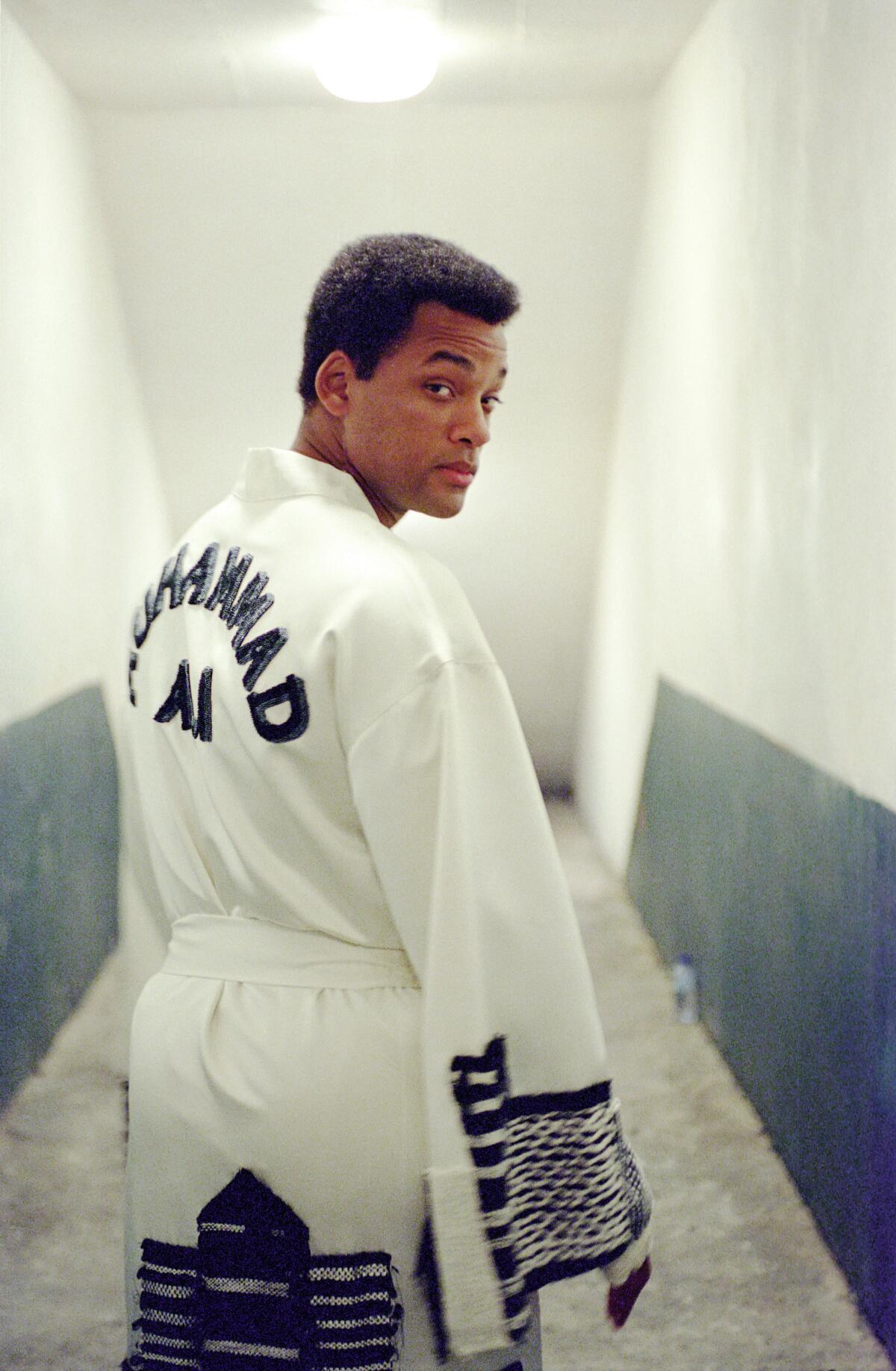 Will Smith wears a boxing robe and looks back at the camera while playing Muhammad Ali in the film "Ali."