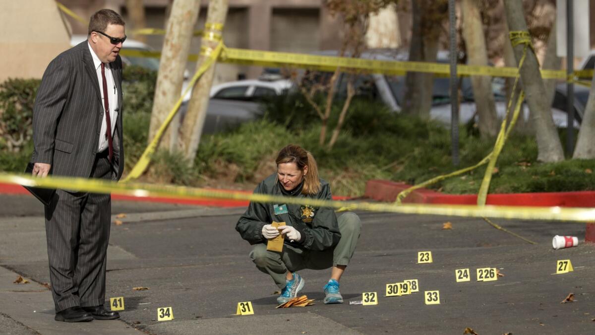 LASD Homicide Bureau Detective Brandt House, left, watches as Tracy Peck gathers evidence from the scene of a gunfire involving a Los Angeles County Sheriff's deputy and a suspect late Tuesday in Santa Clarita.