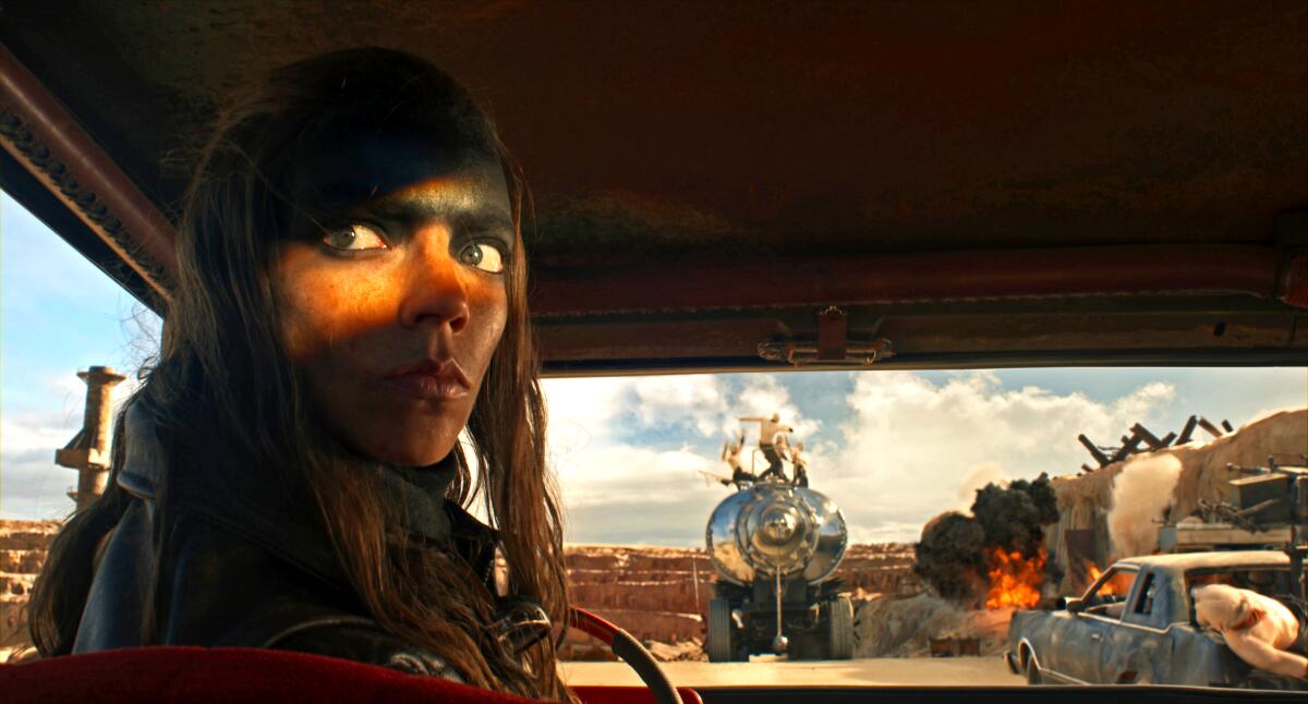 A woman in shadows looks askance in a scene from "Furiosa: A Mad Max Saga."