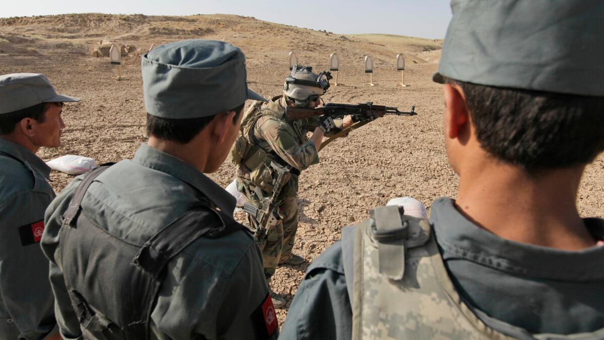 A U.S. soldier shows Afghan police officers how to operate an assault rifle in central Afghanistan in 2009. Around that time, U.S. and U.K. officials supported major anti-corruption investigations in Afghanistan.