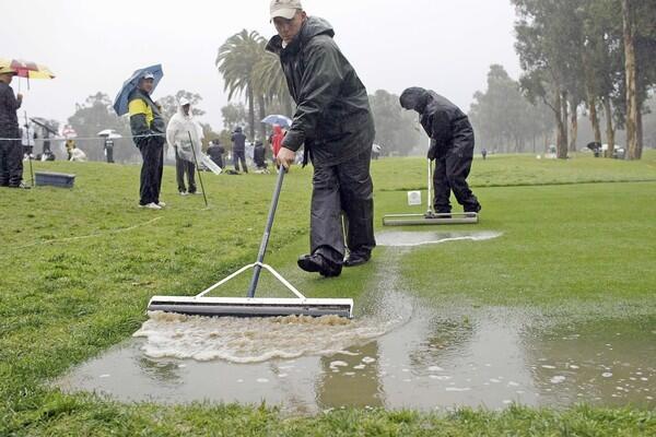 Grounds crew try to keep the tee box at No. 11 playable as rain falls Friday during the second round of the Northern Turst Open at Riviera Country Club.