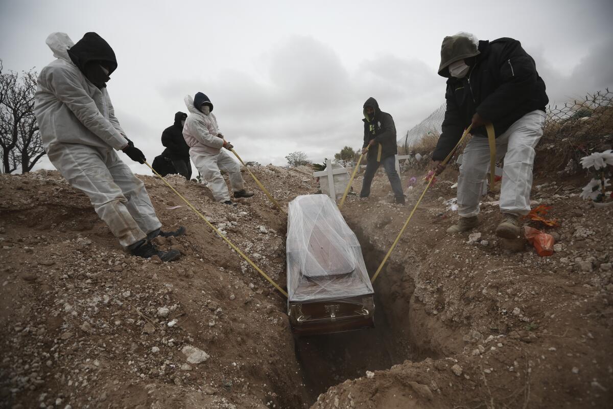 Four men lower a coffin into the ground.