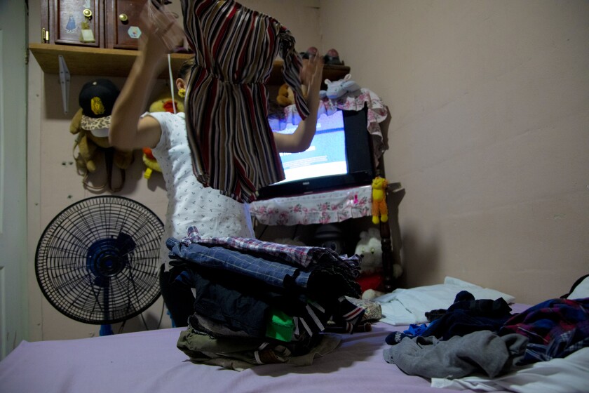 A woman sorts clothes in a room.