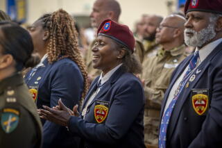 A woman claps while wearing a beret and navy jacket.