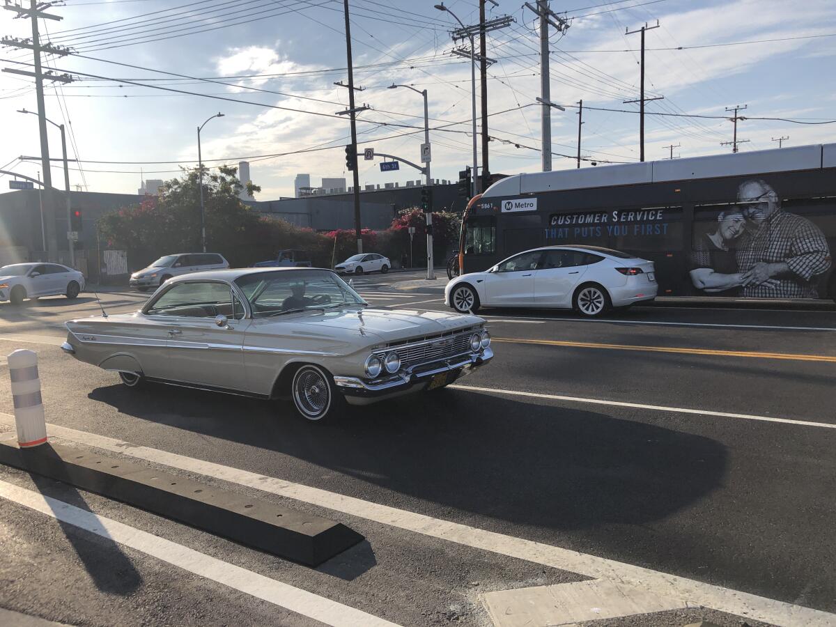 A lowrider drives along the roadway of the 6th Street Bridge as the sun begins to set.