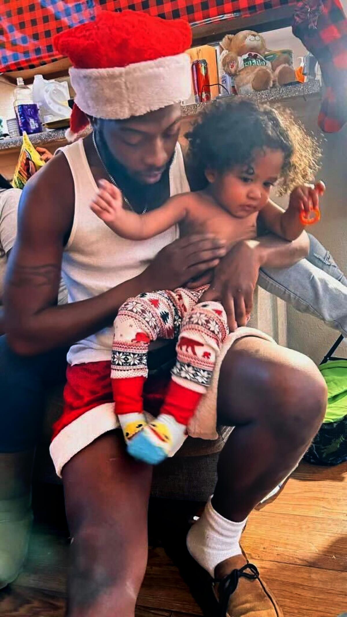 A man in Santa Claus garb holds a child on his lap.