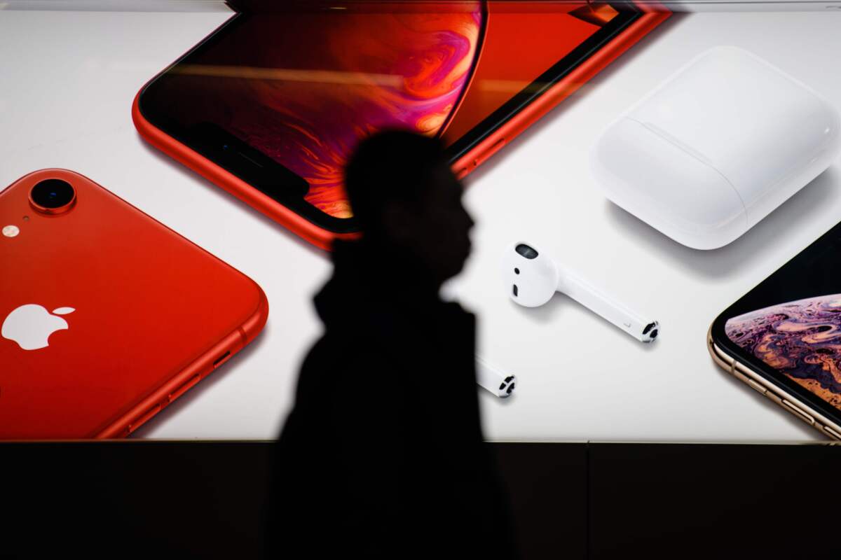 A person's silhouette is shown by a sign displaying an iPhone and other Apple products.