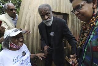 Richard Hunt holds hands with woman as he stands in front of his bronze Ida B. Wells monument sculpture