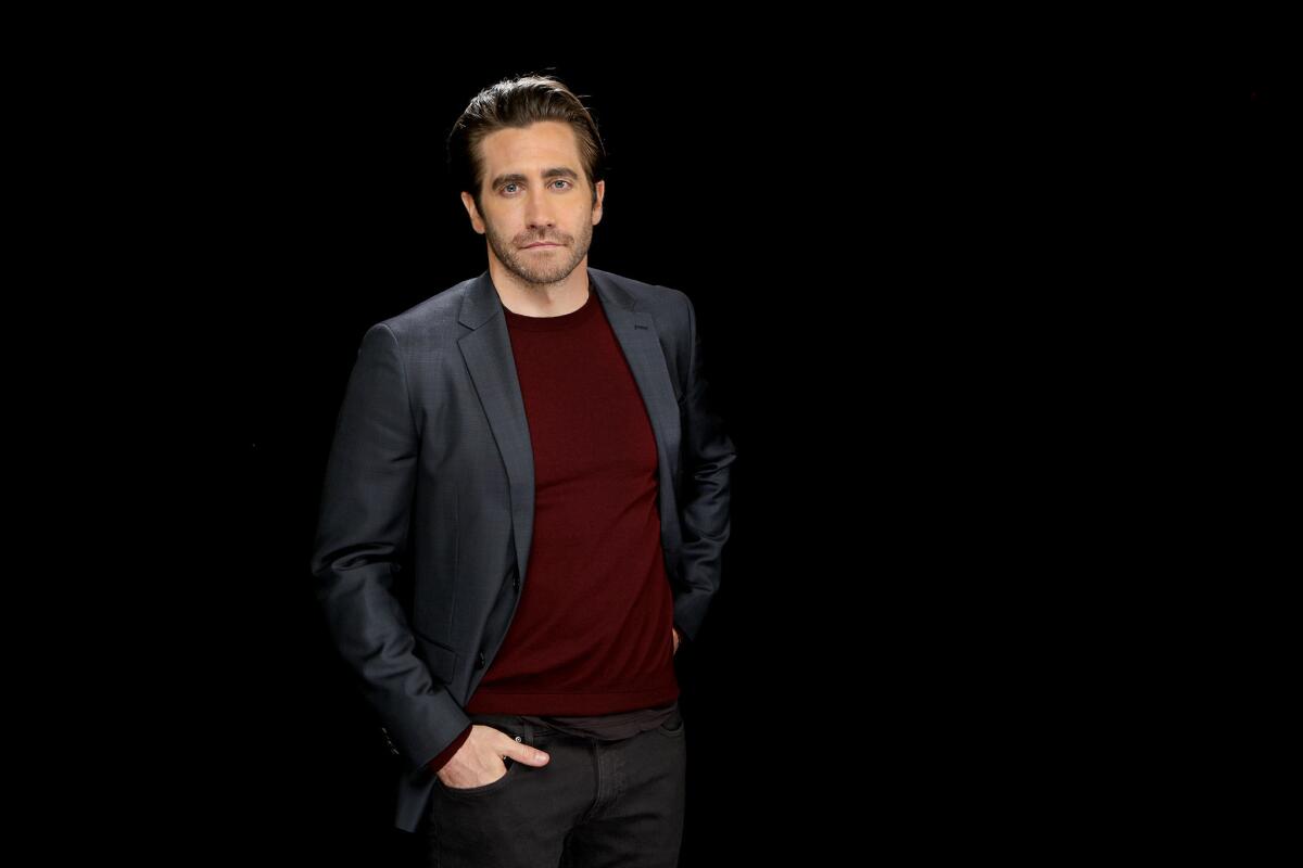 Jake Gyllenhaal in a gray suit posing with his hand in his pocket