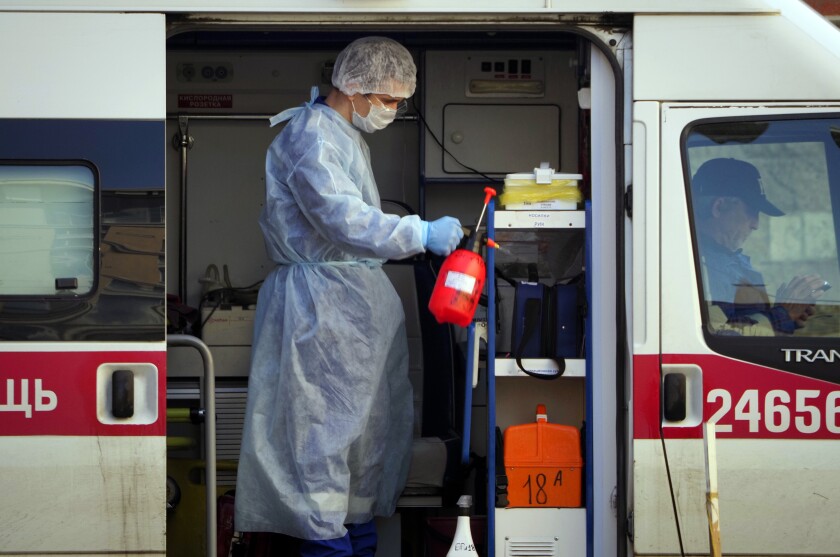 A Russian medical worker sprays disinfectant on his ambulance