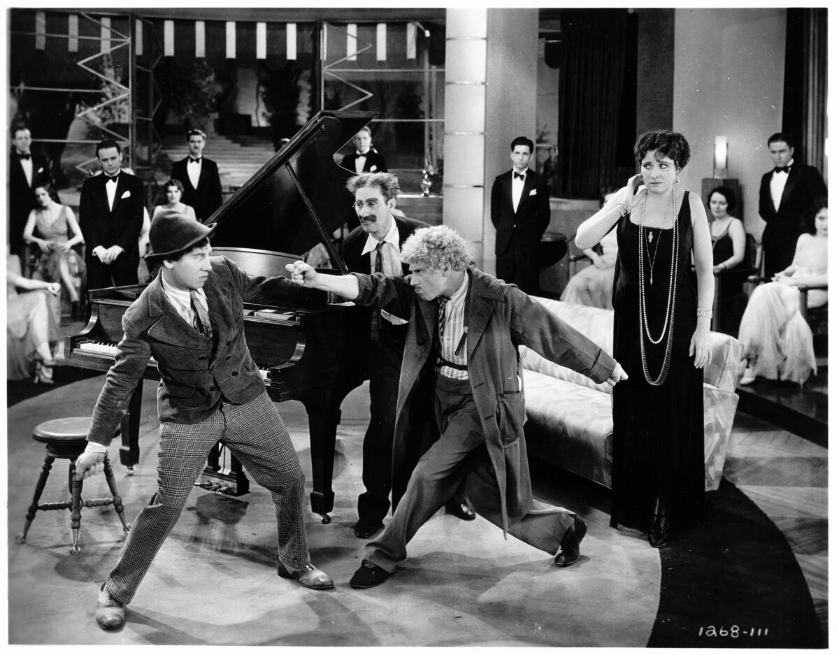 Chico Marx as Signor Emanuel Ravelli, left, Groucho Marx as Captain Jeffrey T. Spaulding (center by the piano), Harpo Marx as The Professor and Margaret Dumont as Mrs. Rittenhouse star in "Animal Crackers."