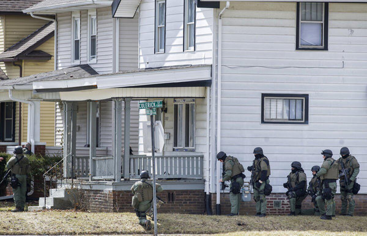 Officers surround a house in Fort Wayne, Ind., where police said a man suspected of killing a bus passenger earlier in the day was holding a 3-year-old child hostage.