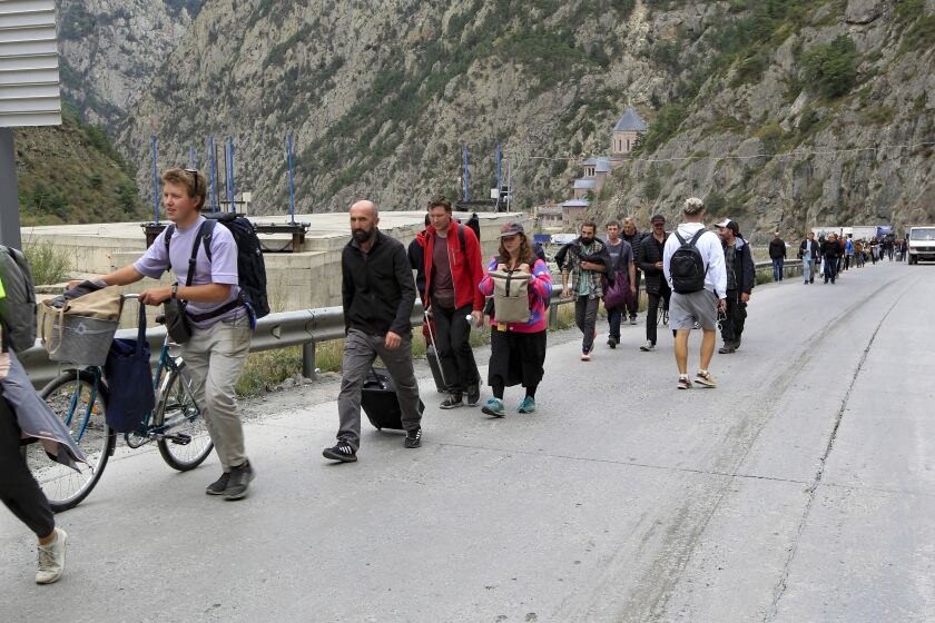 People walk toward the border crossing between Georgia and Russia at Verkhny Lars, as they leave Chmi, North Ossetia–Alania Republic, Russia, Wednesday, Sept. 28, 2022. Long lines of vehicles have formed at a border crossing between Russia's North Ossetia region and Georgia after Moscow announced a partial military mobilization. (AP Photo)