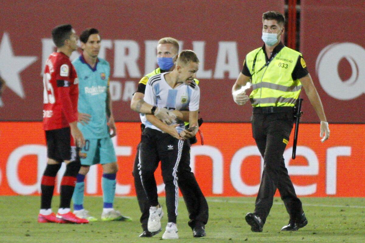 A supporter invades the pitch with FC Barcelona's Lionel Messi