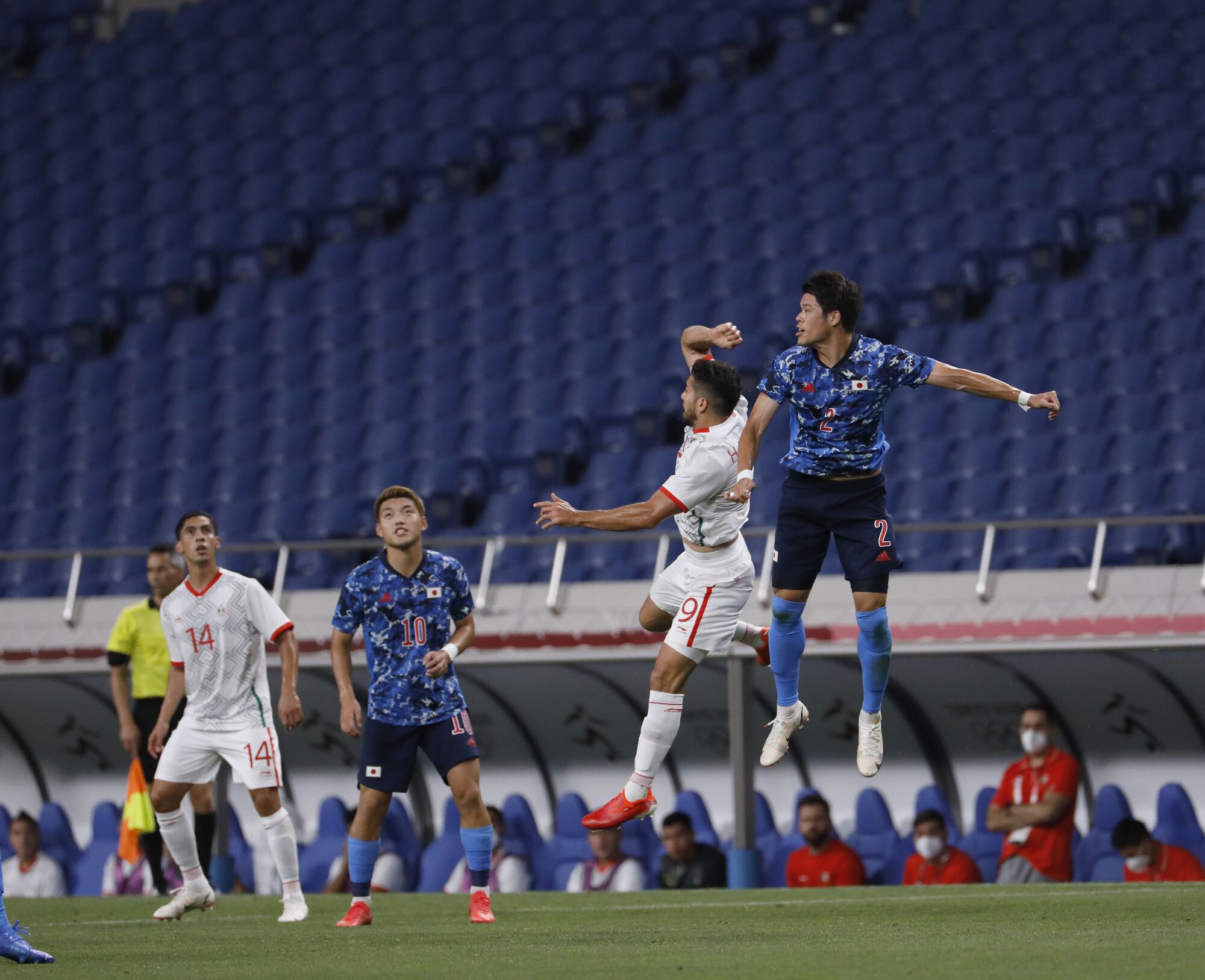 Two men leap into the air. In the background is empty stadium seating.