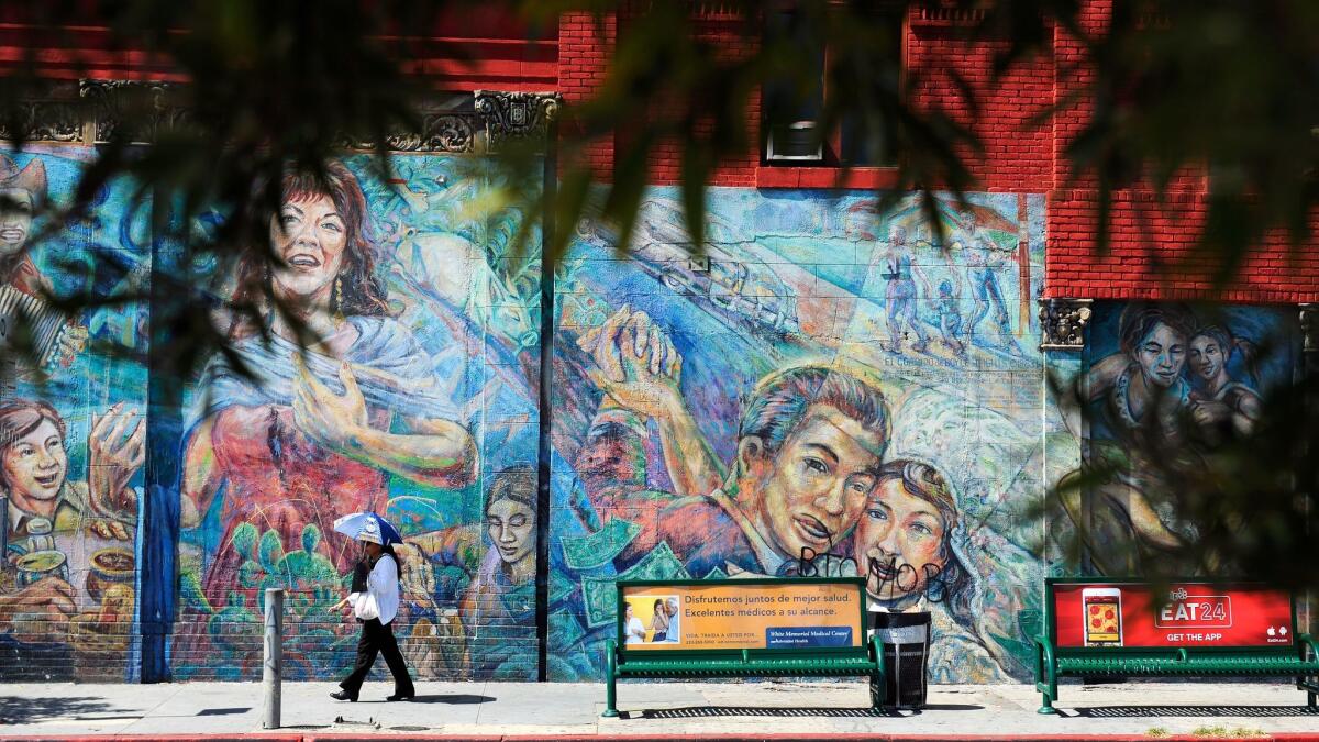 A pedestrian walks past a mural in Boyle Heights in 2015.
