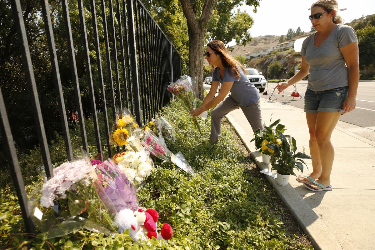 Two women place flowers at a memorial for Mark and Jacob Iskander in Westlake Village in September 2020.