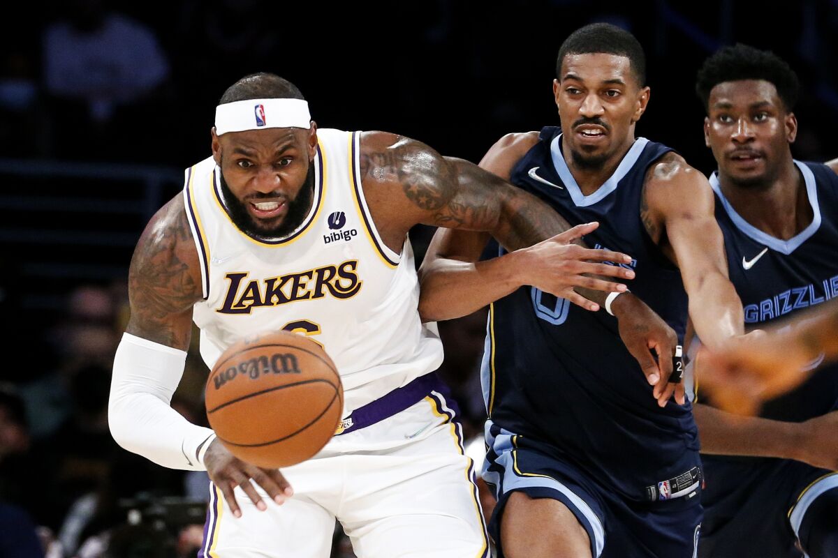 Lakers forward LeBron James and Grizzlies guard De'Anthony Melton chase after a loose ball.