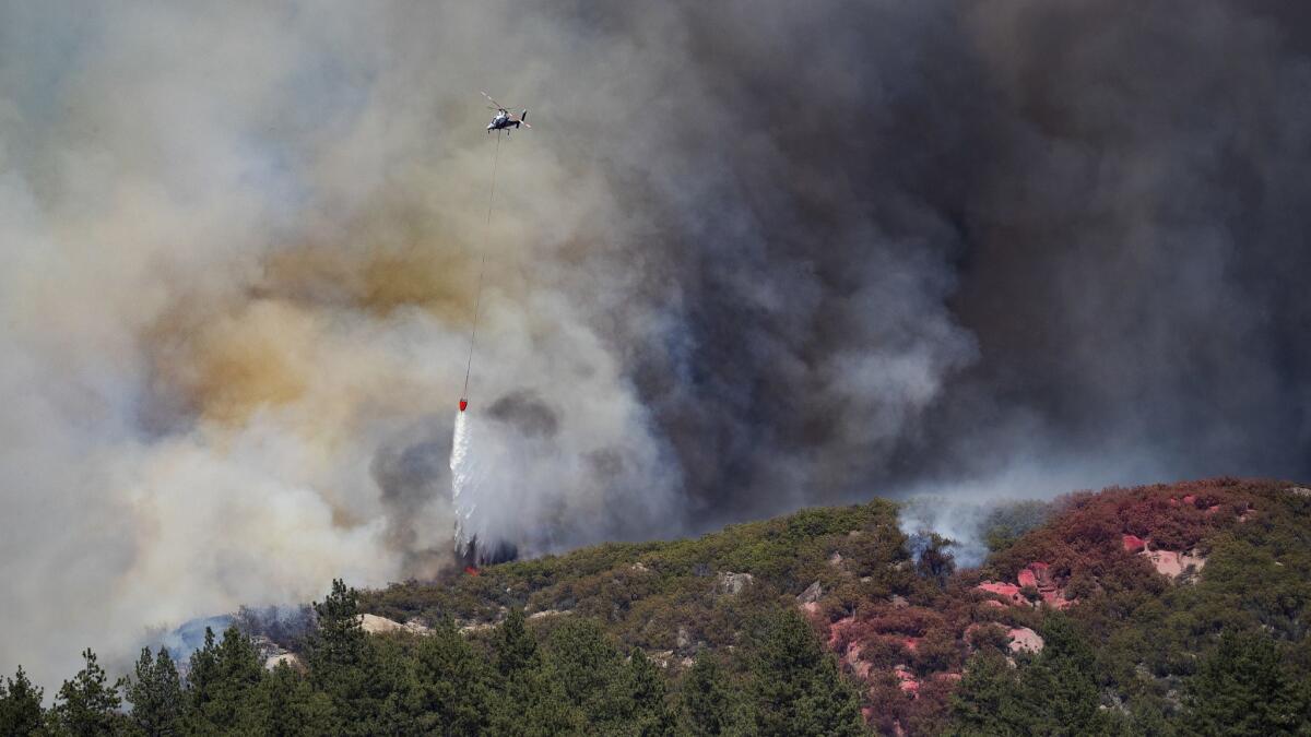 A helicopter drops its load of water as the air assault on the Cranston fire continued Friday in Garner Valley.