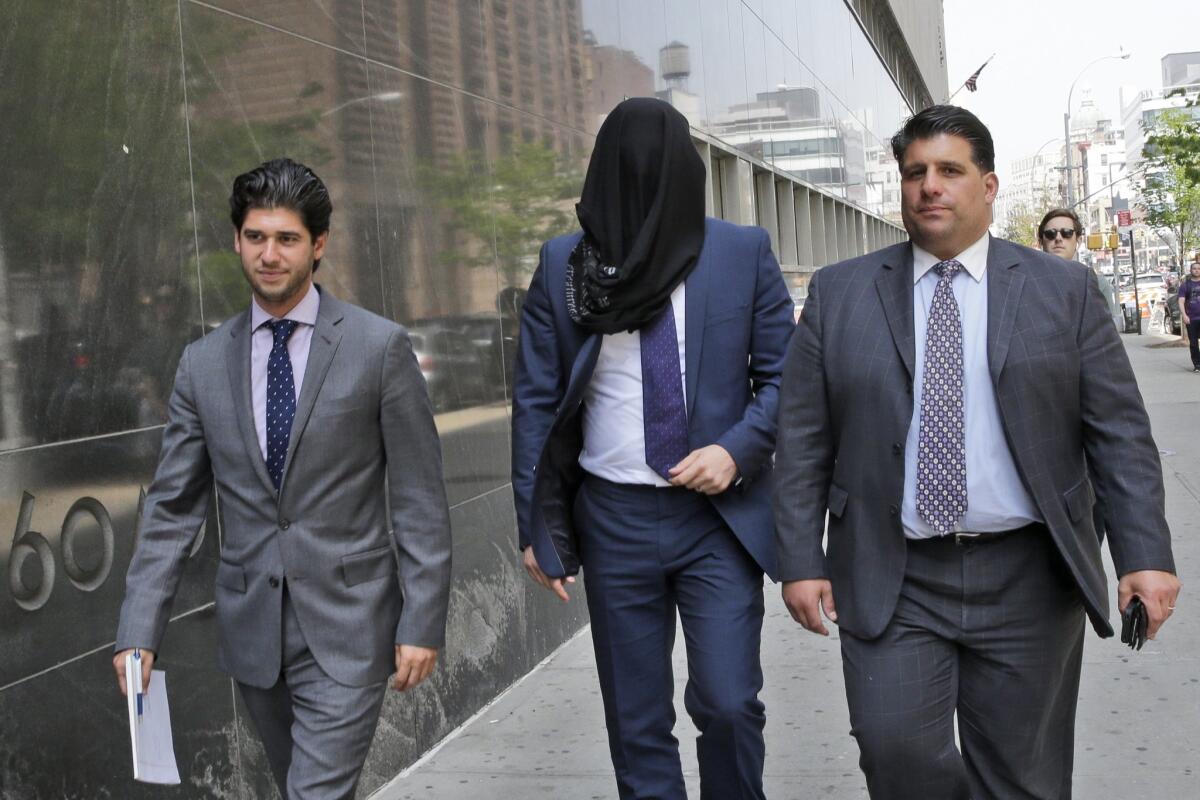 Wojciech Braszczok is led into the court with his face covered Tuesday in New York.