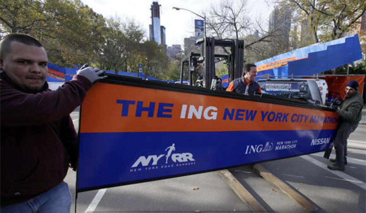 With the crane atop a high-rise that collapsed during Sandy visible in the background, workers assemble the finish line for the New York City Marathon in Central Park on Thursday.