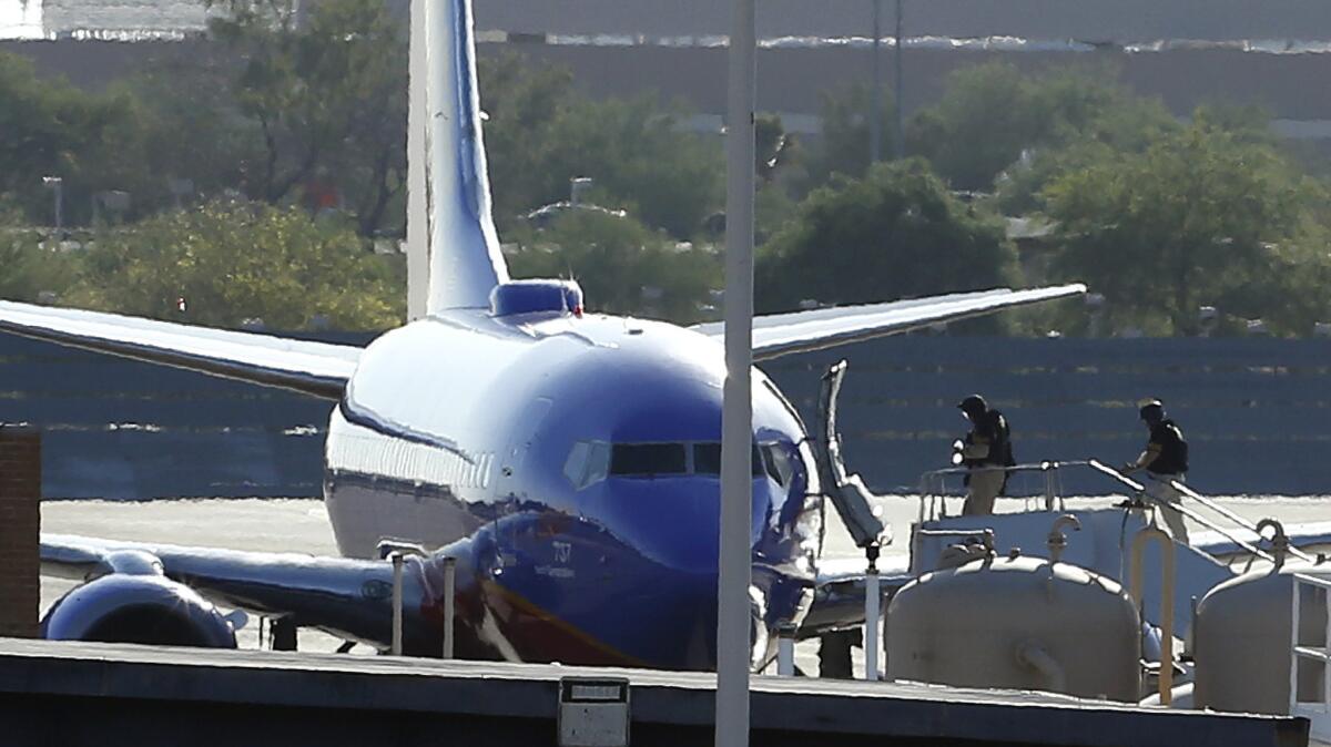 Members of a bomb squad enter a Southwest Airlines plane at Phoenix Sky Harbor International Airport after a phoned-in bomb threat against the flight from Los Angeles to Austin, Texas, led to the plane being diverted Monday afternoon.