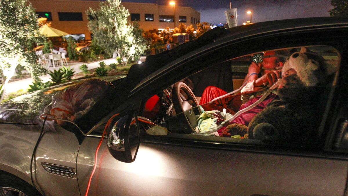 Dyana and Dale Stark use a long extension cord to plug in CPAP machines while they and Dale's mother, who is in the back seat, sleep in their car at the Jewish Family Service's Joan & Irwin Jacobs Campus in San Diego in 2017.