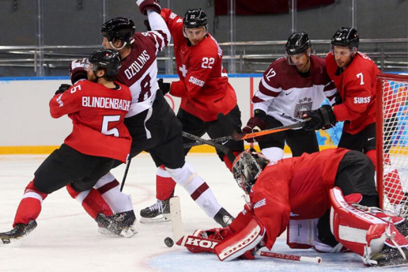 Switzerland goalie Jonas Hiller, bottom right, makes a save during a 1-0 win over Latvia on Wednesday.