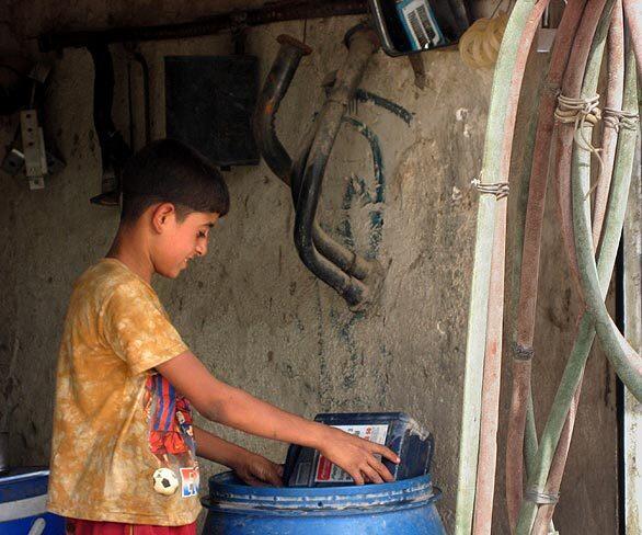 Karrar Raad, 12, works in a muffler shop in Sadr City. His brother Allawi, who is only 10, works in the adjacent garage. The owner offered them work, paying about $3 a day, after he saw them scavenging for cans  a dangerous living in bomb-prone Baghdad. Their father is ill and has no job, so the two are the breadwinners for a family of 10.