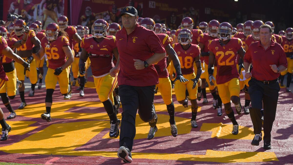 USC Coach Steve Sarkisian, center, runs with his team onto the field before the Trojans' 52-13 victory over Fresno State at the Coliseum on Saturday.