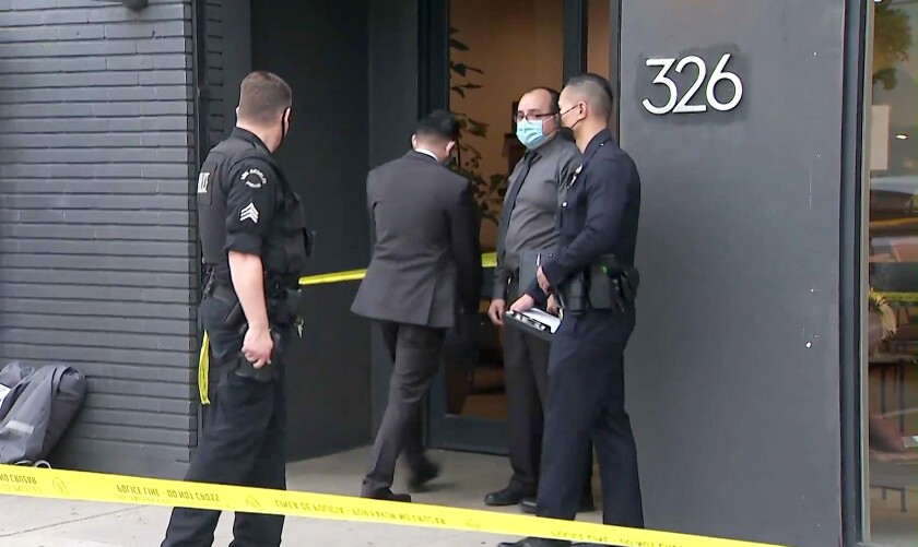 Police officers behind yellow crime scene tape at a storefront
