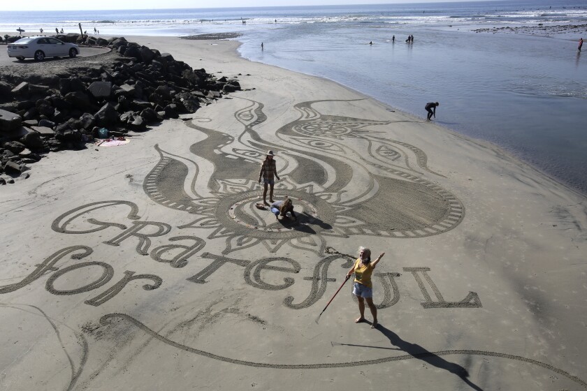 Sand mandala artist Sharon Belknap, right, asks a spectator "What are you grateful for?" 