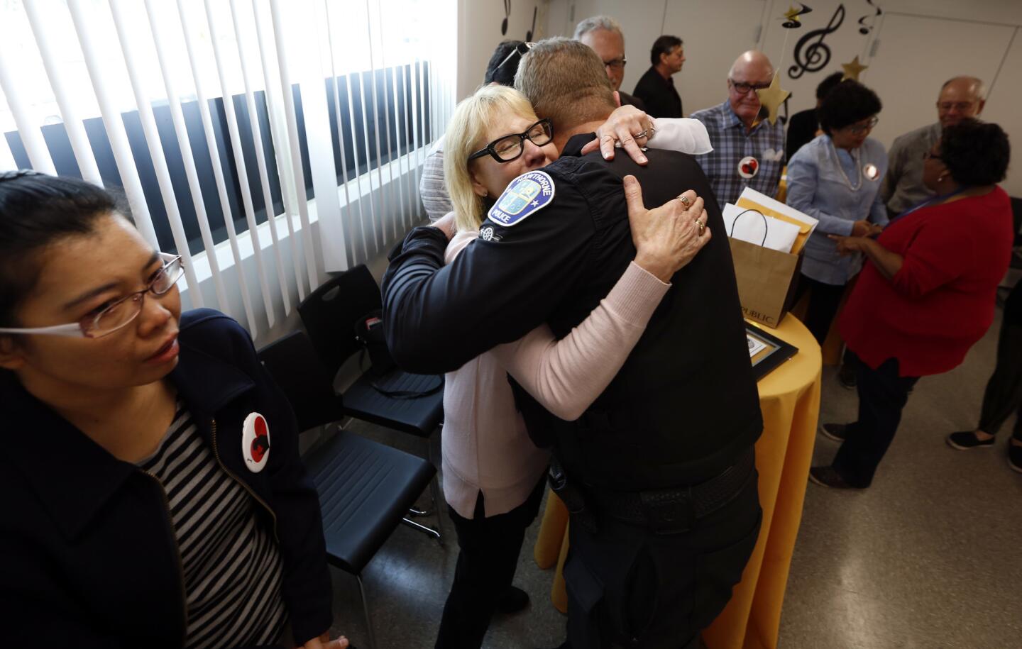 Sheri Kessel, center, hugs Hawthorne Police Officer Sean Judd at Children of Promise Preparatory Academy in Inglewood, which renamed its music classroom in honor of Kessel's son Benny Golbin.