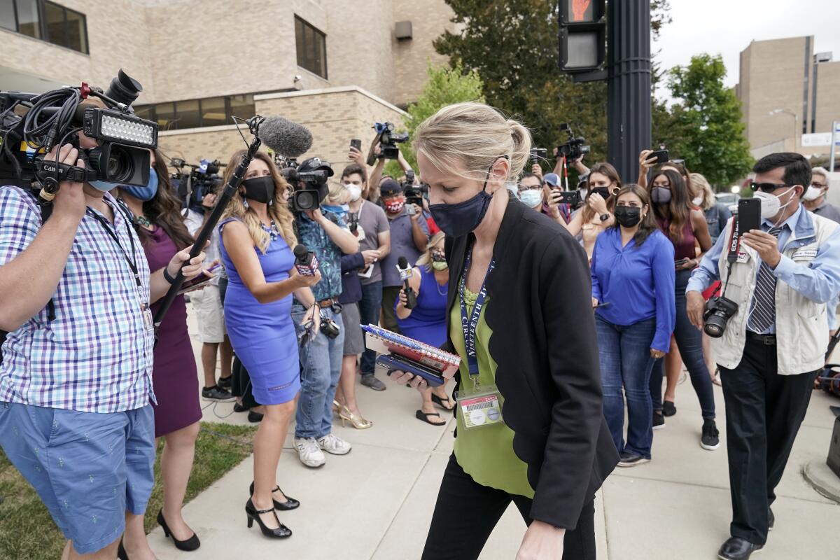 Kasey Morgan, a public information officer for the Lake County Court, walks away from reporters outside the Lake County courthouse following the extradition hearing for Kyle Rittenhouse Friday, Aug. 28, 2020, in Waukegan, Ill. A judge agreed Friday to delay for a month a decision on whether the 17-year-old from Illinois should be returned to Wisconsin to face charges accusing him of fatally shooting two protesters and wounding a third during a night of unrest following the weekend police shooting of Jacob Blake in Kenosha. (AP Photo/Morry Gash)