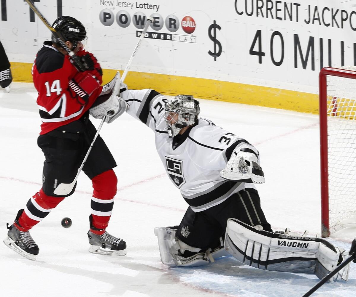 Kings goalie Jonathan Quick knocks New Jersey's Adam Henrique off the puck on Monday night.