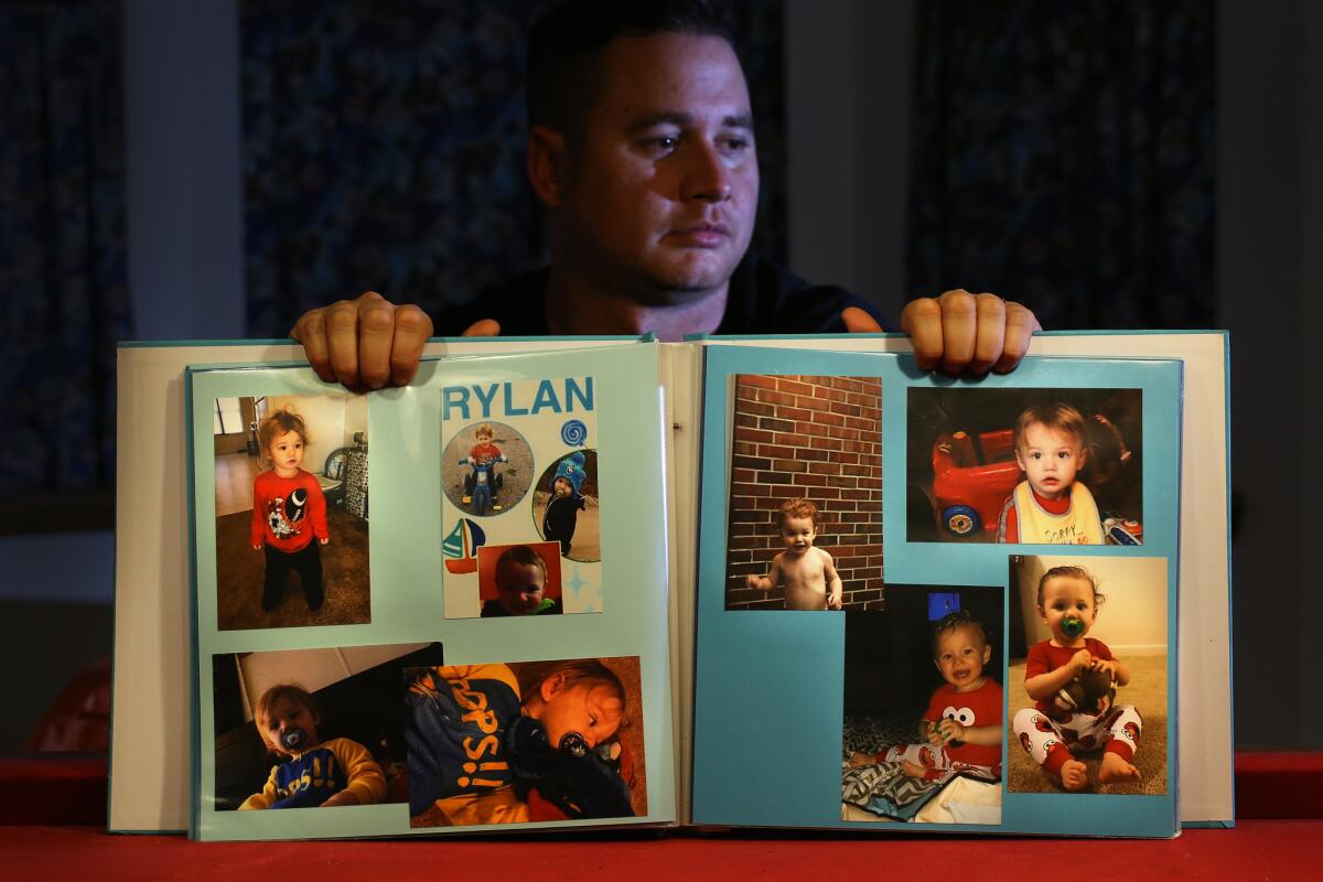 Corey Ott displays a book of photographs of his son, Rylan Ott, who apparently drowned in a North Carolina pond while under the care of his mother, Samantha Bryant.