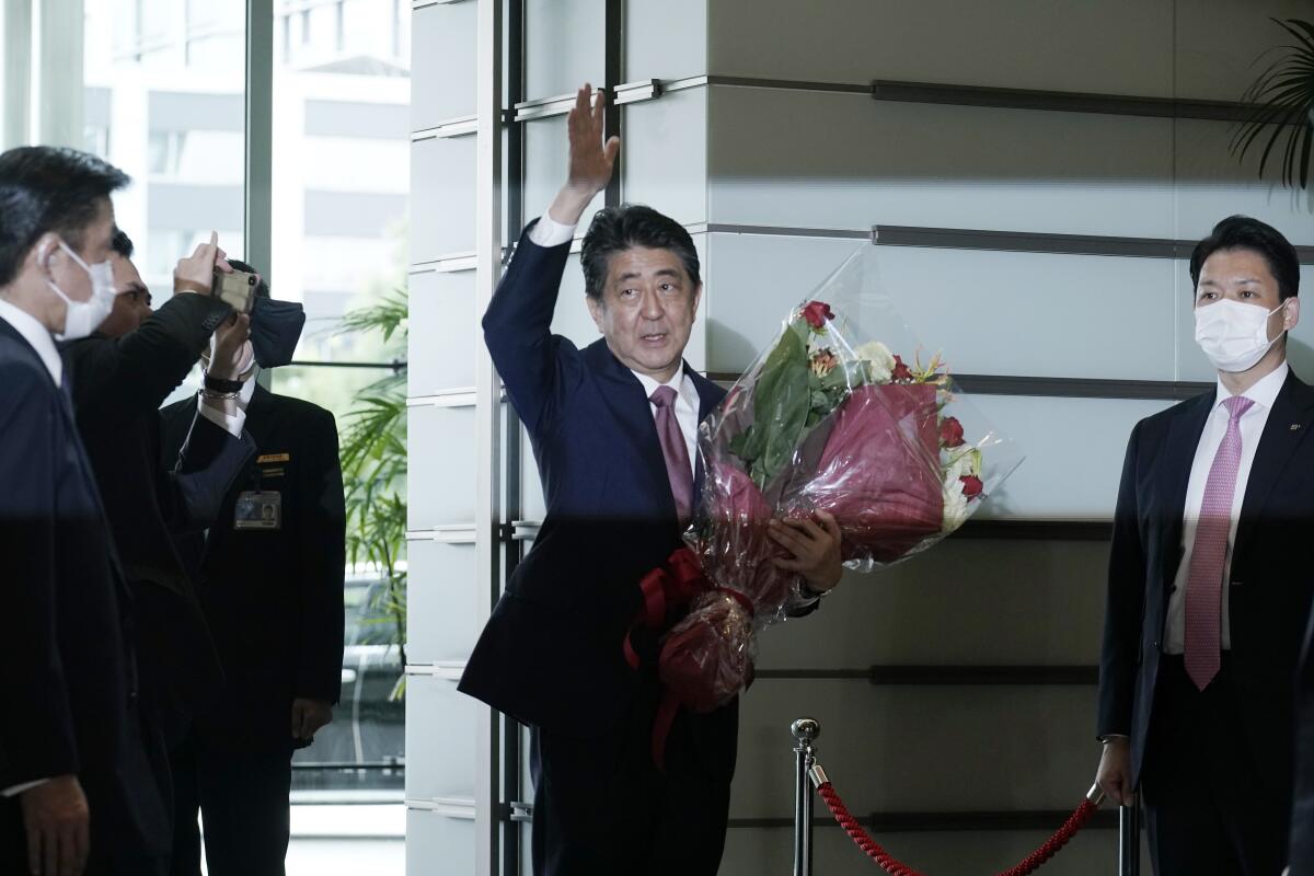 Then-Prime Minister Shinzo Abe waving and holding flowers