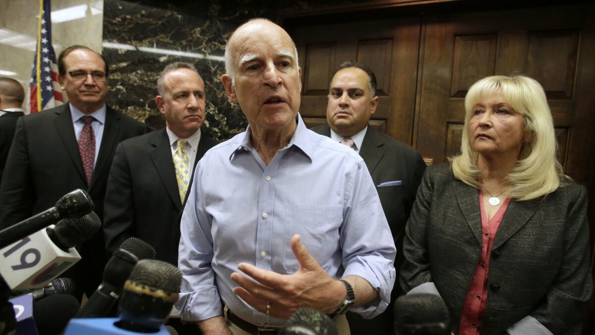 Gov. Jerry Brown, center, responds to a question concerning a compromise plan reached on reducing the state's prison population, during a Capitol news conference in September 2013.