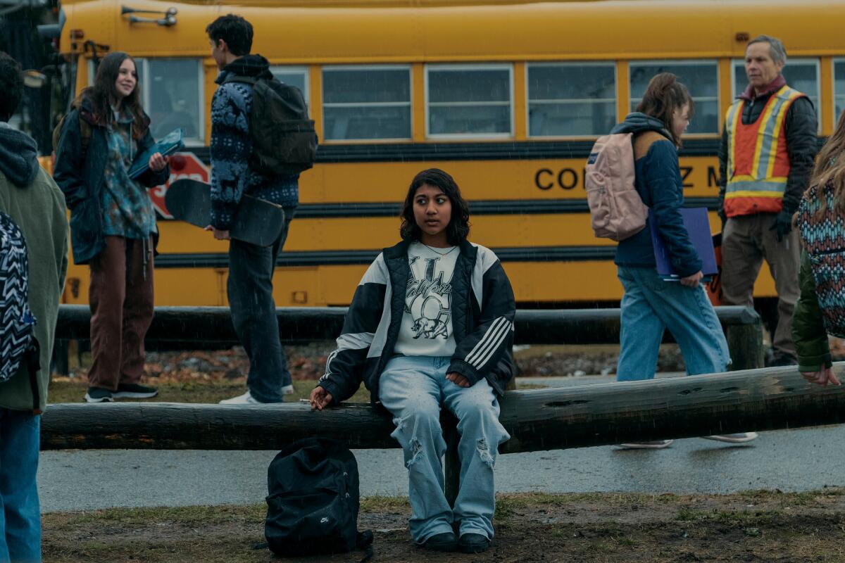 Vritika Gupta sits on a school bench next to a bus.