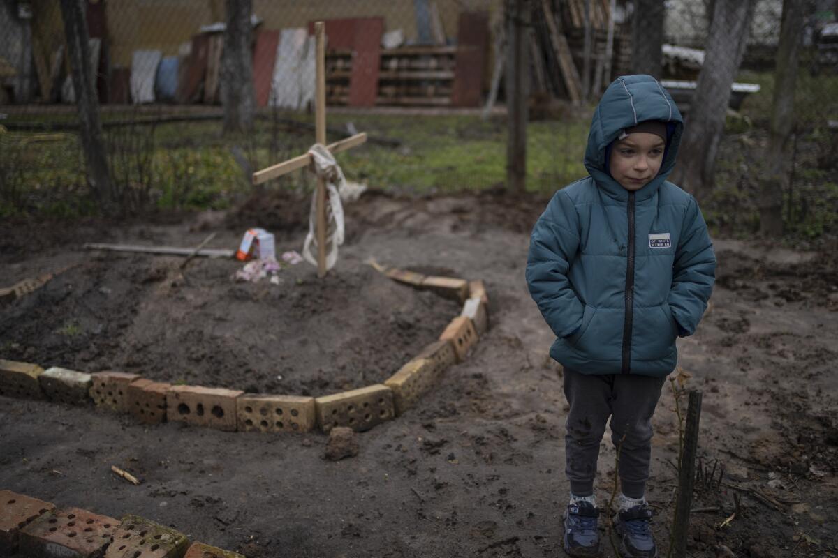 Boy standing near the grave of his mother.