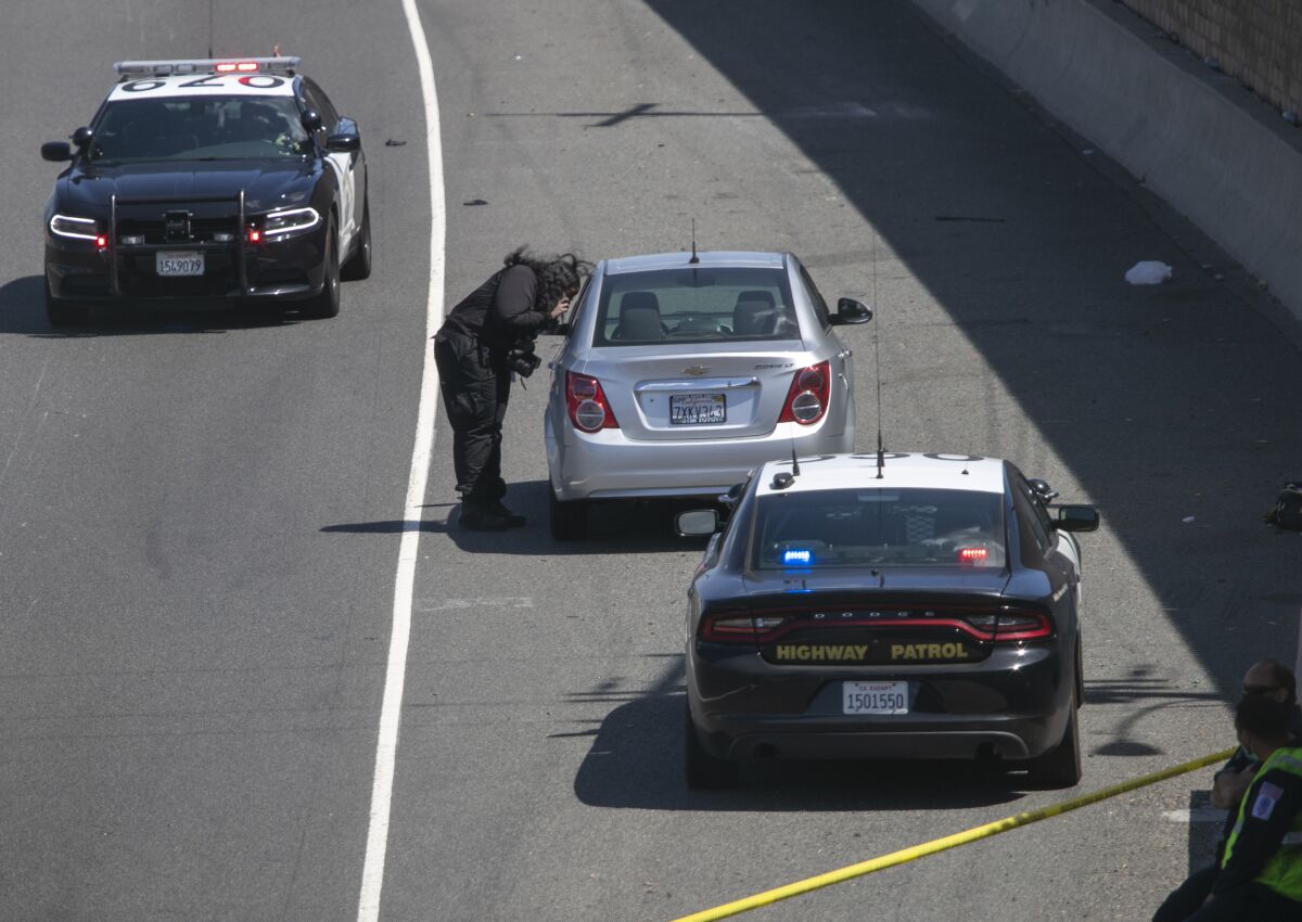 A crime scene investigator photographs the Chevy Cruze sedan with a bullet hole in the hatch.