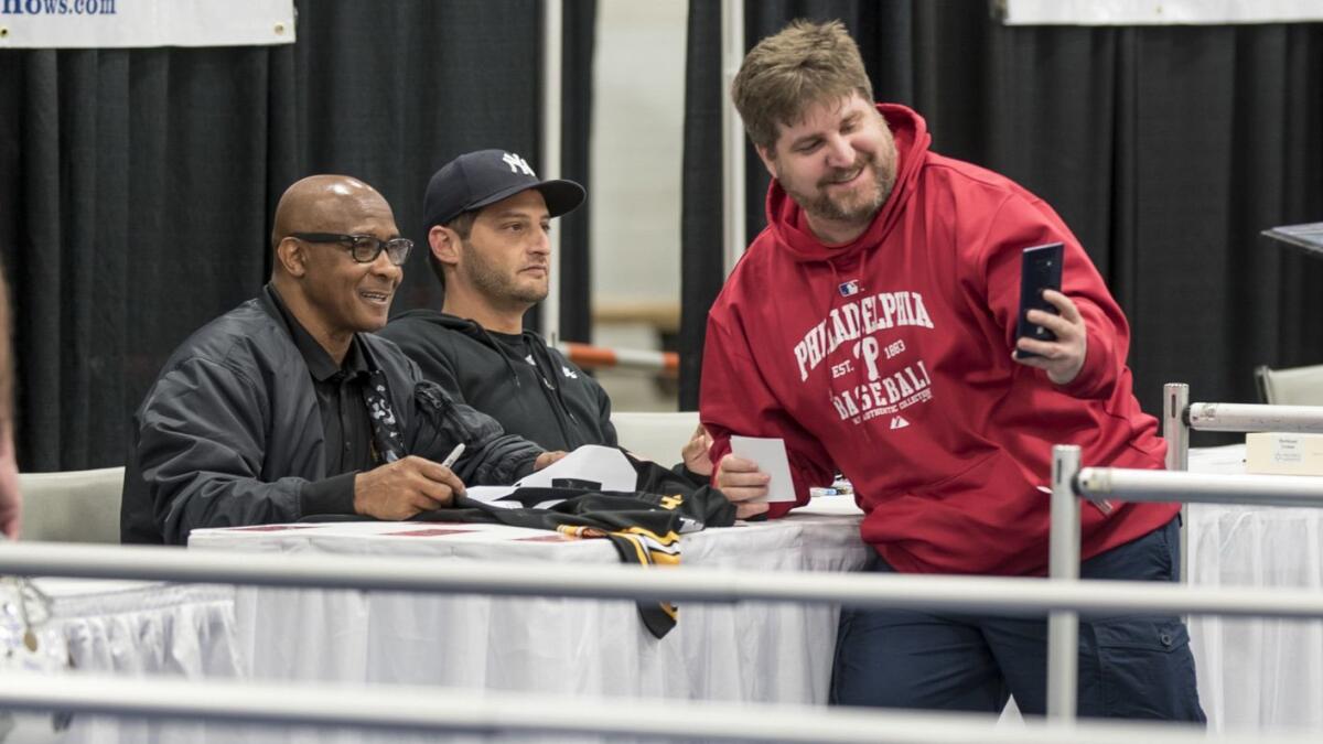 USC athletic director Lynn Swann poses for pictures with a fan while signing autographs at a sports memorabilia convention in Chantilly, Va., on Saturday.