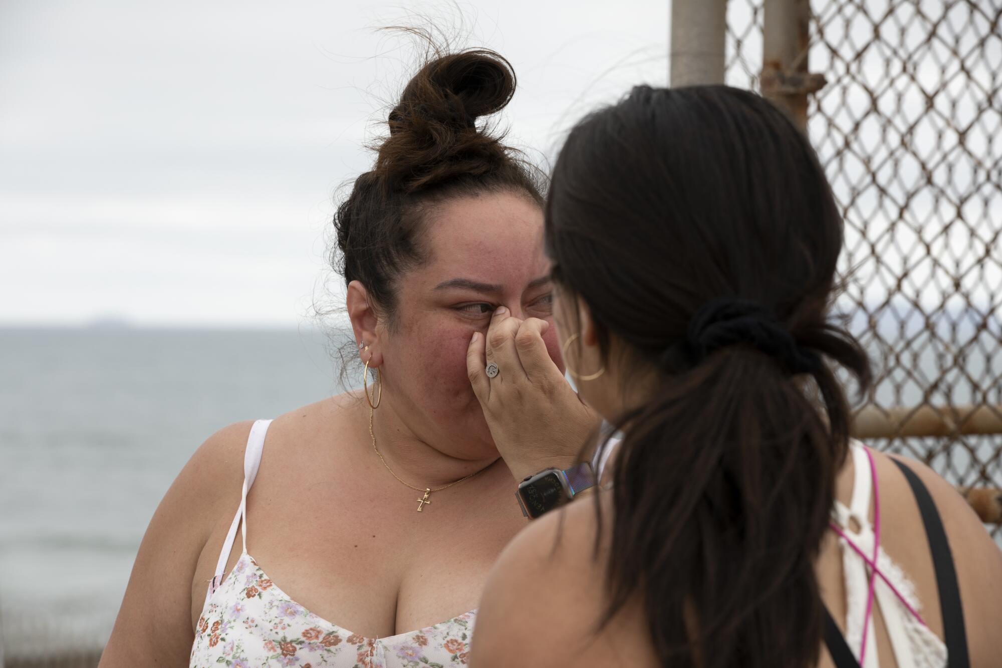 Two women stand close together near the border.