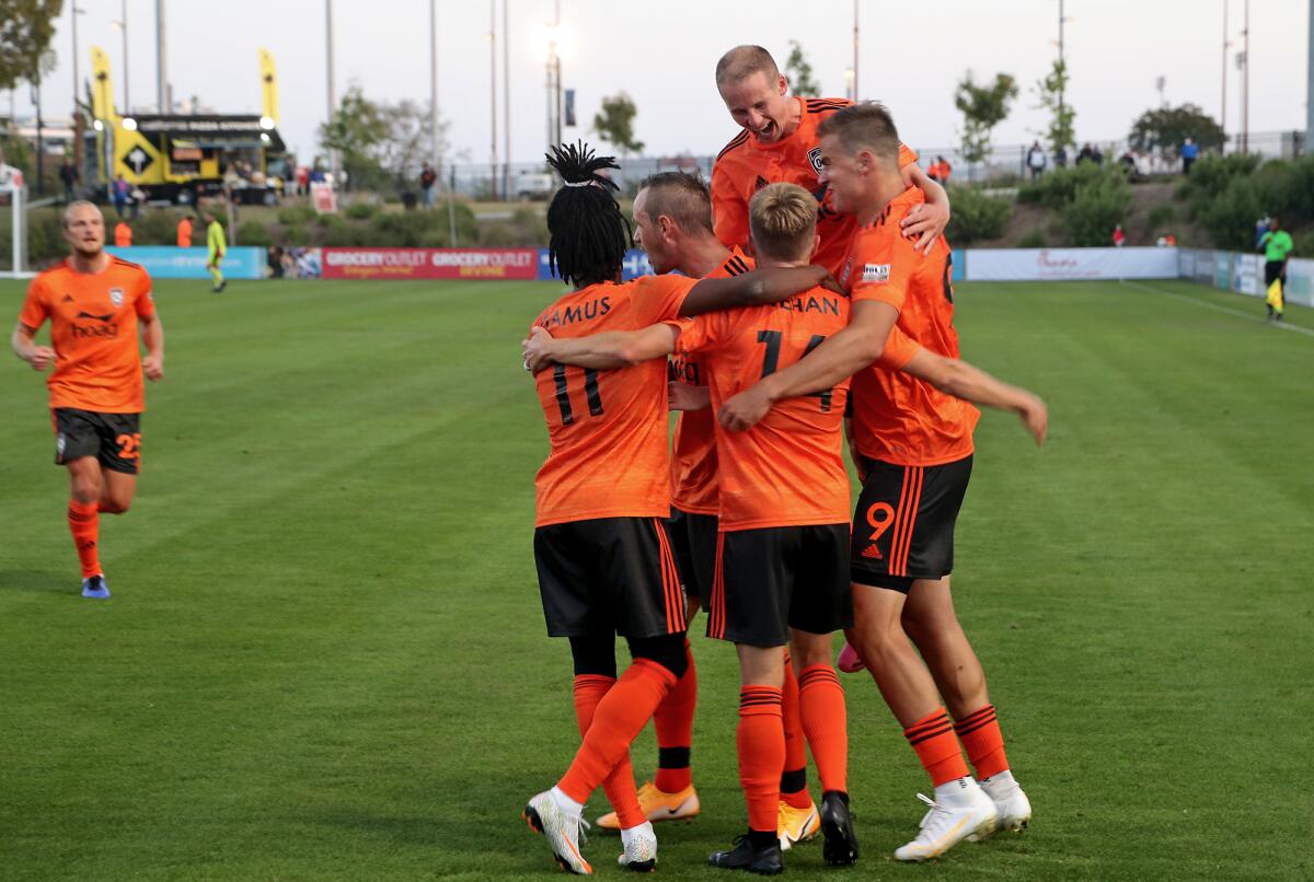Orange County Soccer Club players celebrate a goal by midfielder Chris Wehan, bottom second from right, in the home opener.