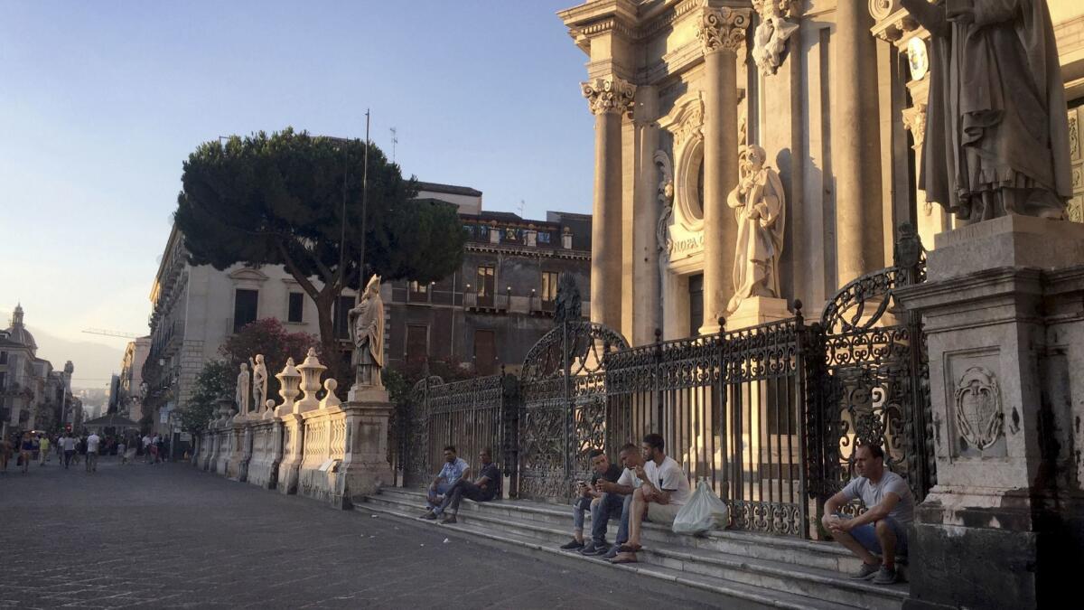At dusk, immigrants often gather on the steps of Catania's Saint Agatha Cathedral.
