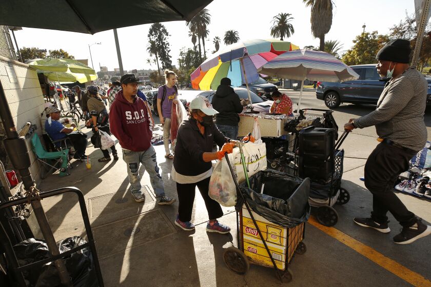 LOS ANGELES, CA - NOVEMBER 19: Pedestrians, some without masks walk along South Alvarado Street between Wilshire and 7th Street in the MacArthur Park area Thursday afternoon that is filled with street vendors as California Gov. Gavin Newsom has announced a mandatory overnight stay-at-home order that will be instituted throughout most of California to combat a surge in new coronavirus cases, a measure that comes just days after the governor enacted a dramatic rollback of reopening in much of the state. "The virus is spreading at a pace we haven't seen since the start of this pandemic and the next several days and weeks will be critical to stop the surge. We are sounding the alarm," Newsom said in a statement released Thursday afternoon. "It is crucial that we act to decrease transmission and slow hospitalizations before the death count surges. We've done it before and we must do it again." MacArthur Park on Thursday, Nov. 19, 2020 in Los Angeles, CA. (Al Seib / Los Angeles Times