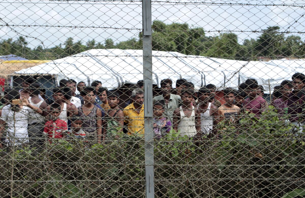 Rohingya refugees gather near a fence 