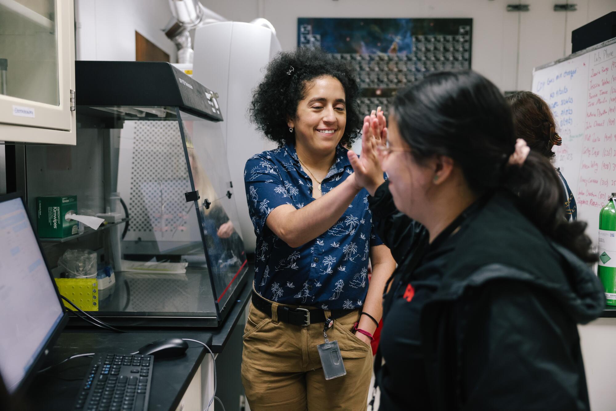  Julia Chavez and Cathy Trejo high-five in a room.