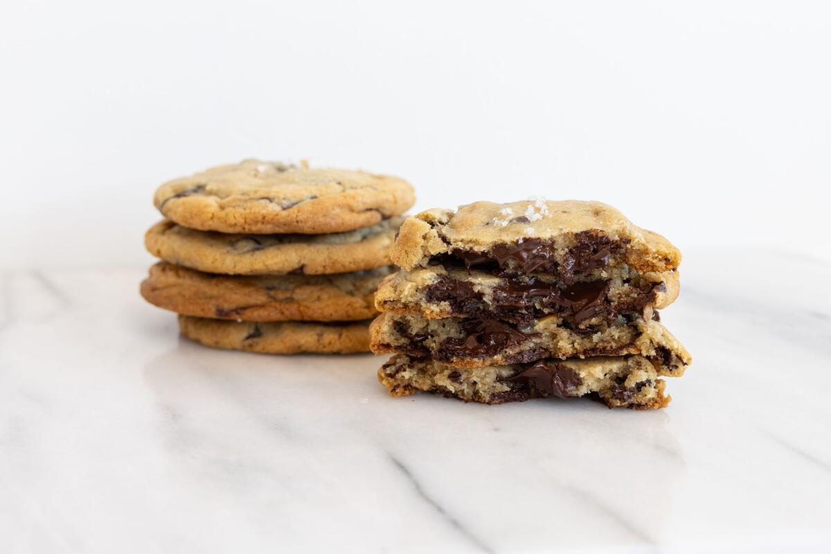 Two stacks of chocolate chip cookies, one of whole cookies and one of partial cookies showing chocolate inside